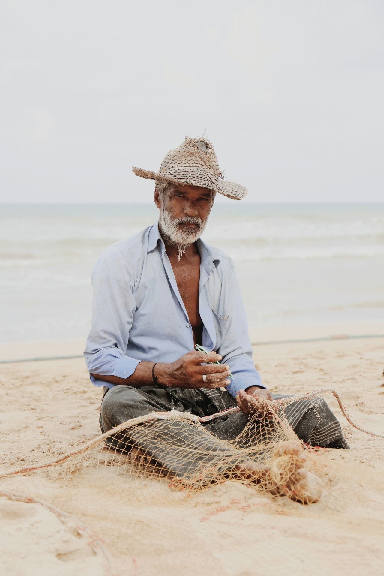 A man sitting on a beach next to a net